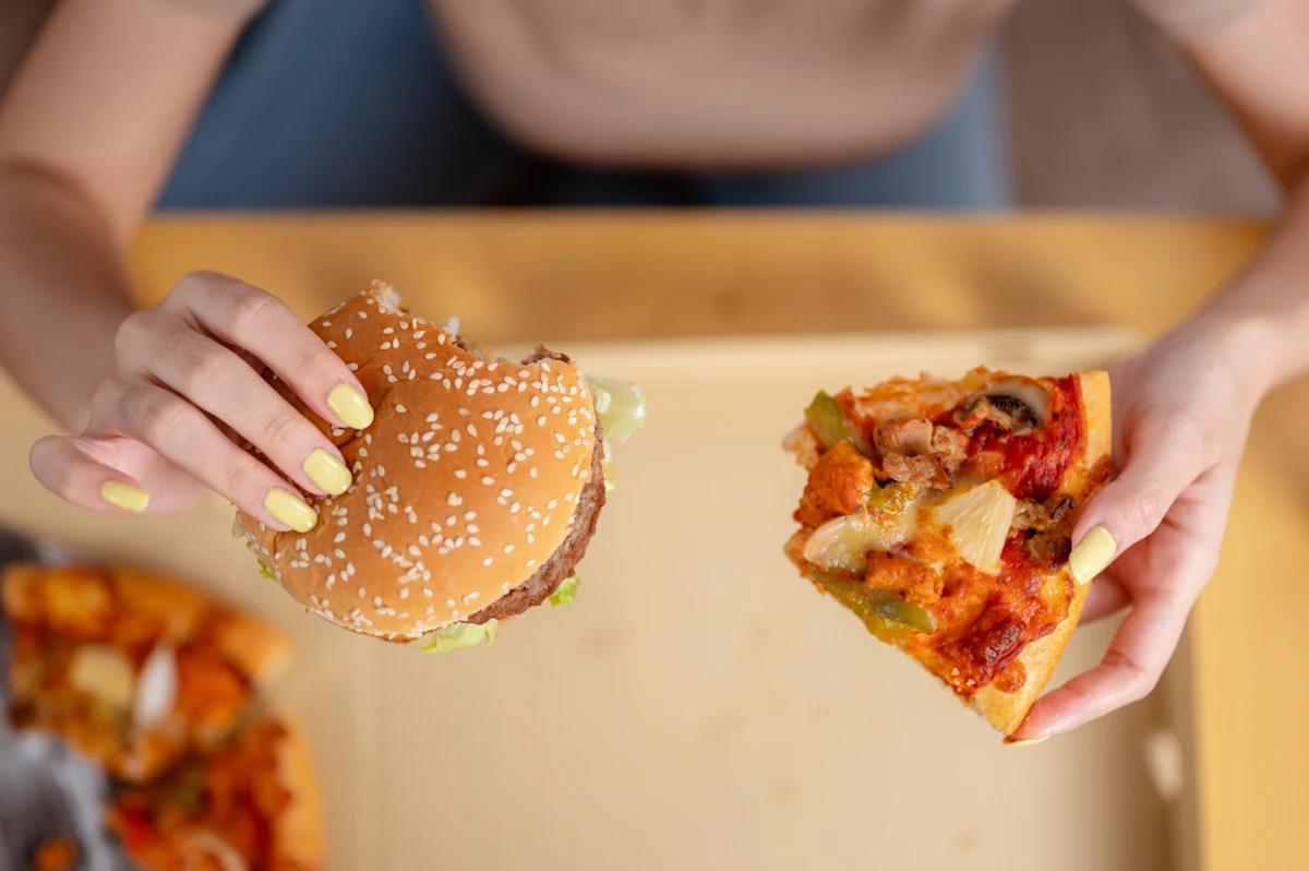 Une personne qui mange de la pizza et un humburger